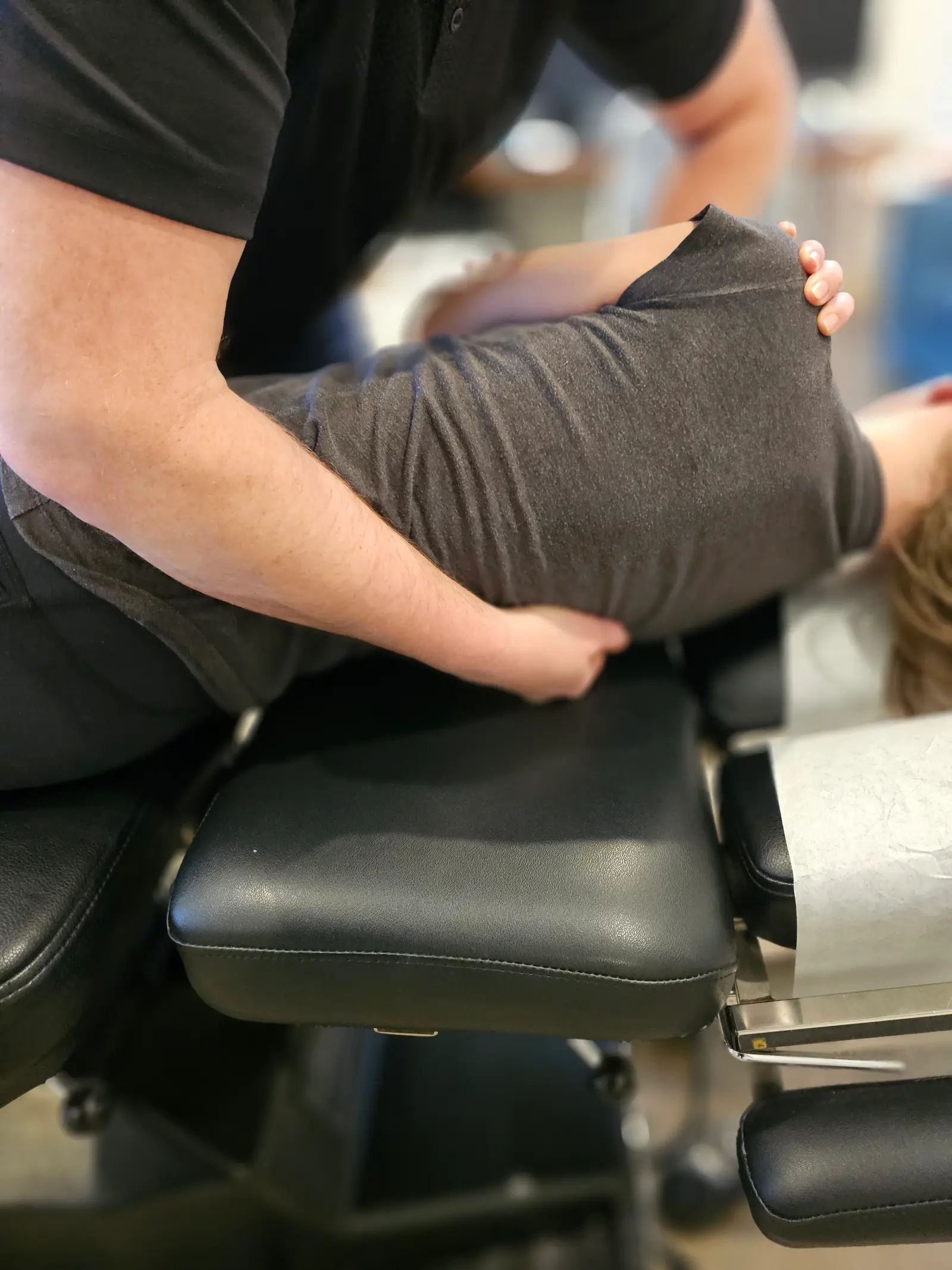 A chiropractor’s hands on a seated patient’s shoulder and upper back